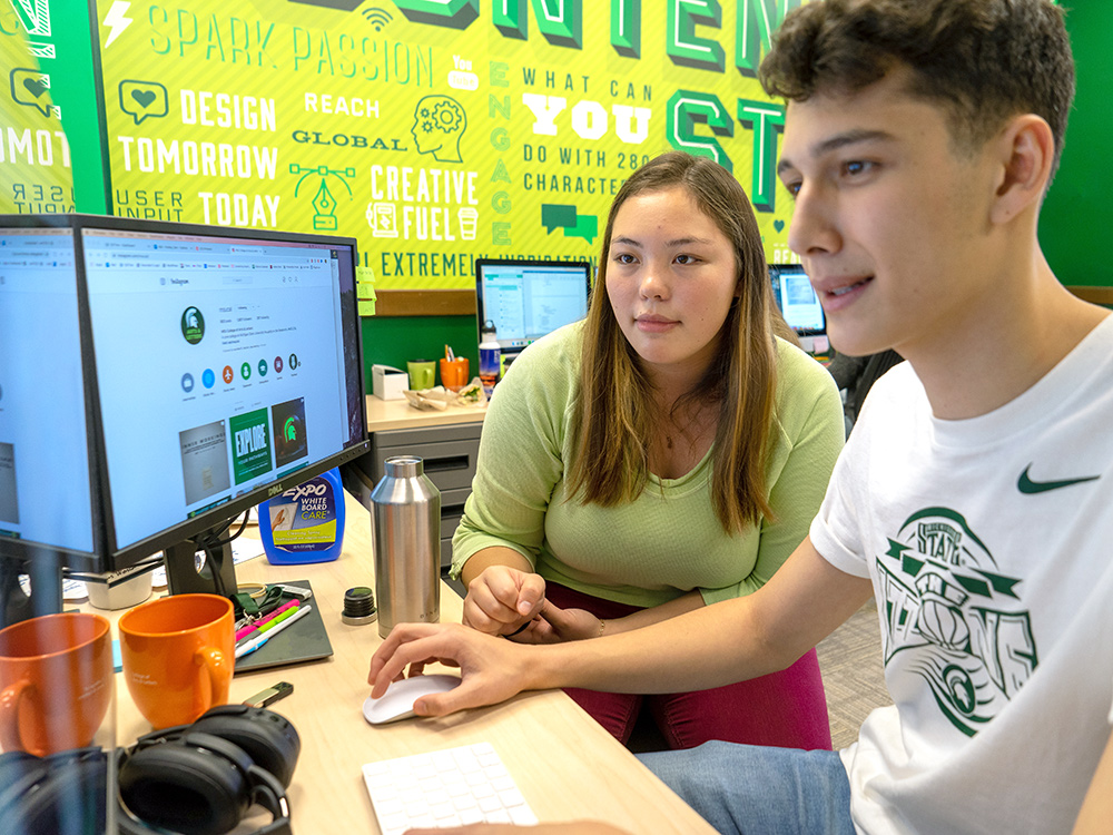 Two content studio interns working collaboratively at a computer